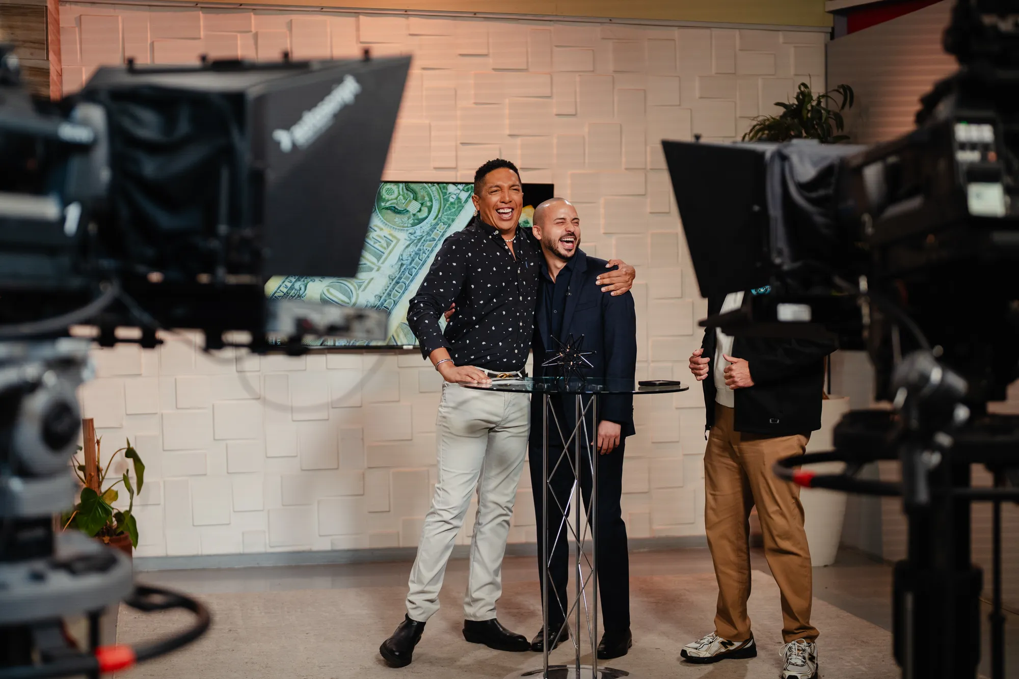 Gabriel laughing with the host on a TV set, between studio cameras